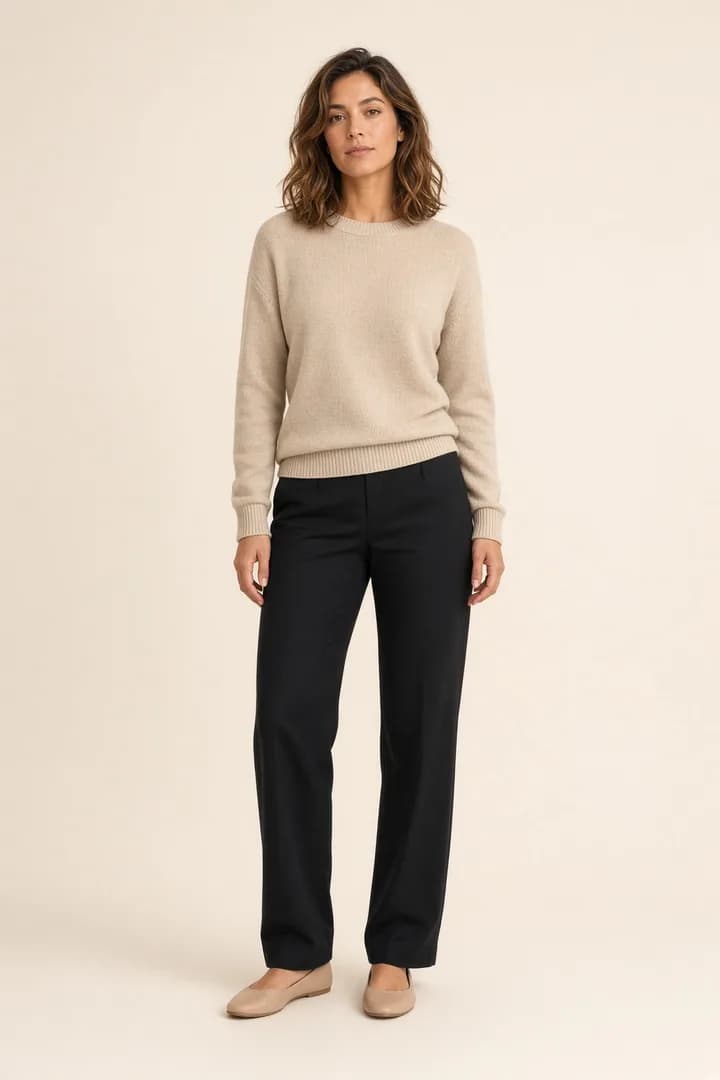 Model steht in beigem Pullover und schwarzer Hose